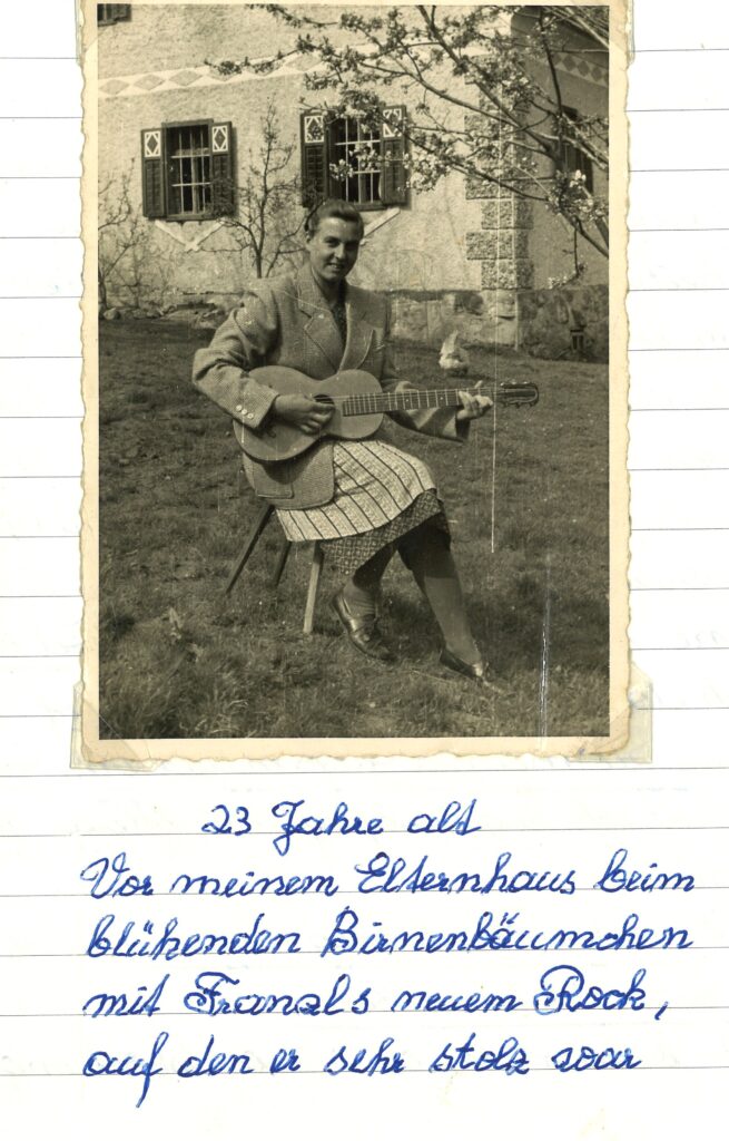 Foto von Hilde Rauch vor ihrem Elternhaus beim blühenden Birnenbäumchen mit neuem Rock und Gitarre, 23 Jahre alt am 1. Mai 1956
