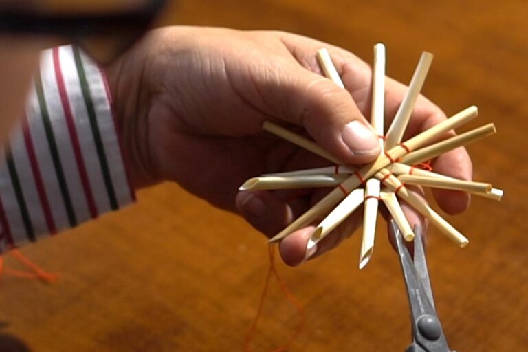 Eine Person, die eine Schere und ein Bündel Streichhölzer hält.